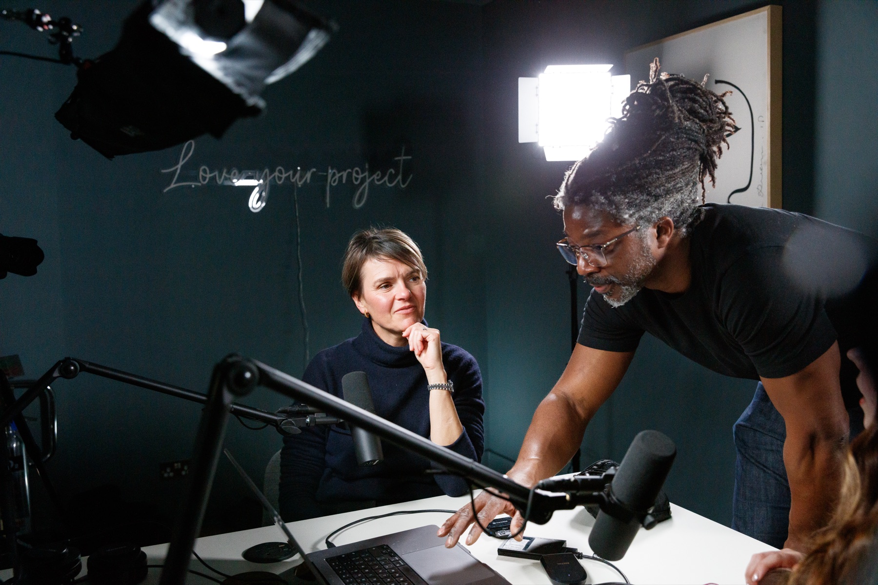 Kevan Smith working a podcast set: lights, boom microphones and a dark teal studio wall