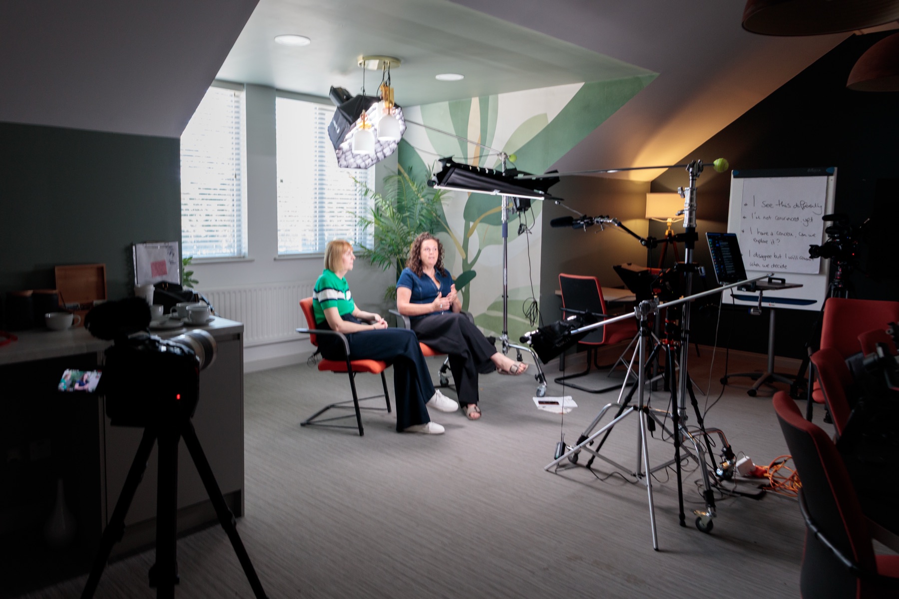 Two people in conversation on a lit interview set built inside an office