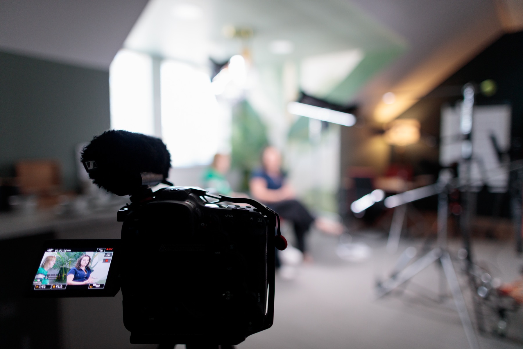 View past the camera towards two speakers in conversation